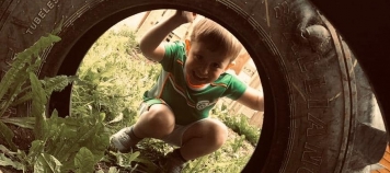Child peeking through a tyre at Muck Angels